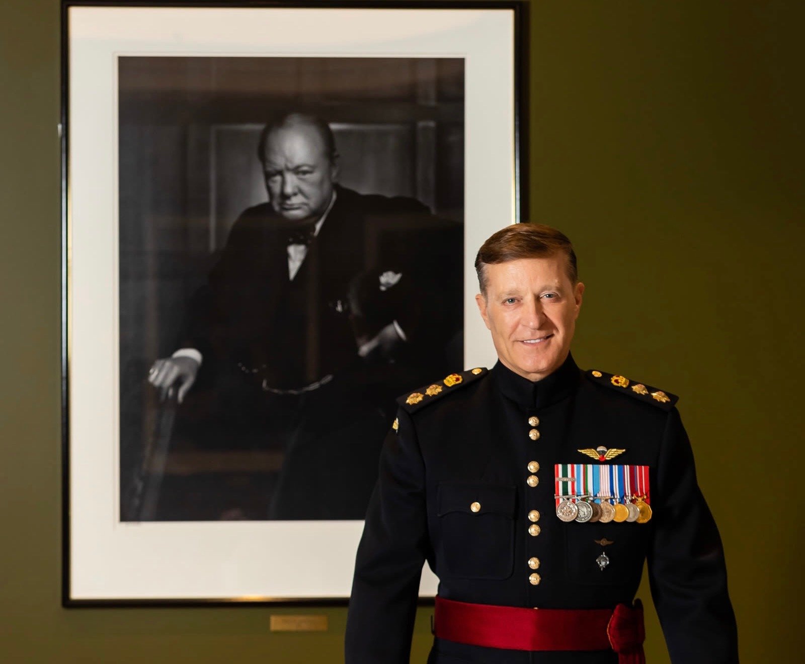 Bryan Brulotte in Canadian Army dress uniform beside a portrait of Winston Churchill
